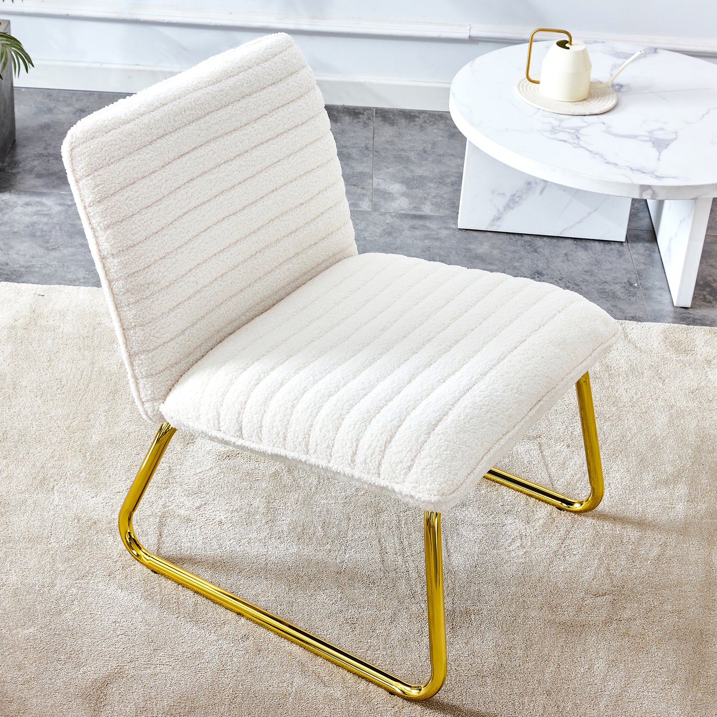 One White minimalist armless sofa chair with plush cushion and backrest paired with golden metal legs