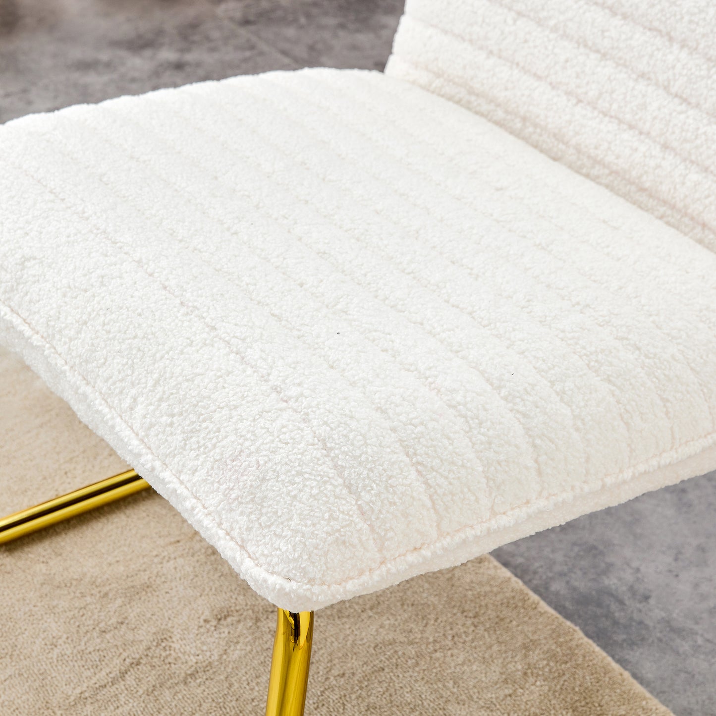 One White minimalist armless sofa chair with plush cushion and backrest paired with golden metal legs